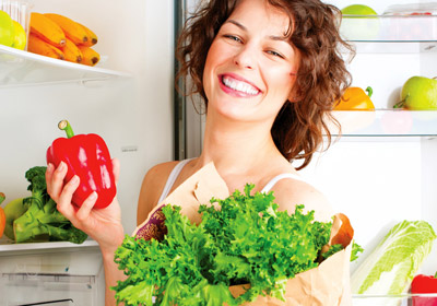 Junge Frau vor einem Kühlschrank mit gesunden Lebensmitteln
