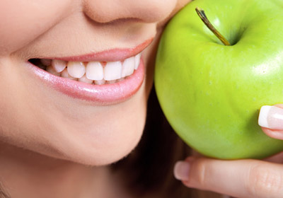 Gesunde Zähne und ein grüner Apfel